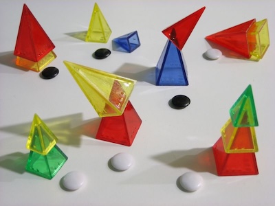 A table with groups of colored plastic pyramids. Each group is marked with a black stone or a white stone.