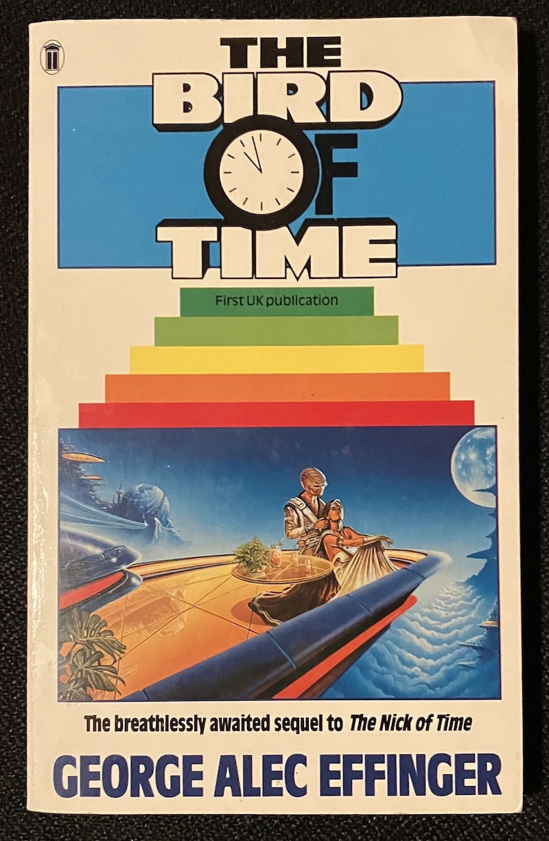 The cover of "The Bird of Time". A man in a peculiar helmet and a woman wearing a low-cut gown and a high-cut cape; they are relaxing on a futuristic balcony with an antigravity cocktail. A subtitle notes "First UK publication".